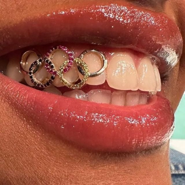 It’s the Olympics week! German basketball player @nyarasabally is set to shine at the Paris 2024 Olympic Games with a ✨very✨ special smile. 
She sported a gold and gem-studded grillz inspired by the Olympic rings, created by the New York-based company @fineassfronts. The piece features small coloured gemstones set in 14k gold. ✨
#blackbeautymag #olympics #nyarasabally #paris2024